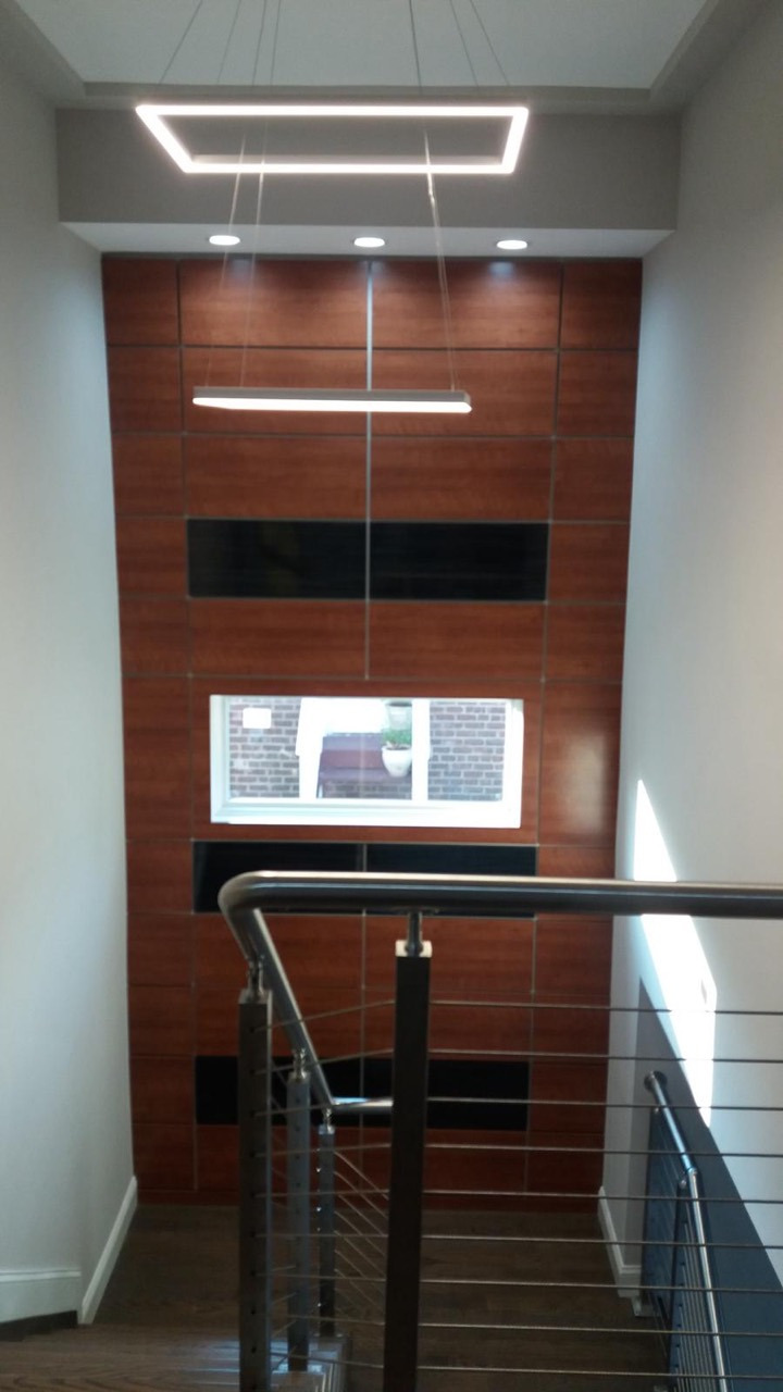 Interior stairwell with cable railing, dark wood stairs, wood-paneled feature wall, and rectangular pendant lights